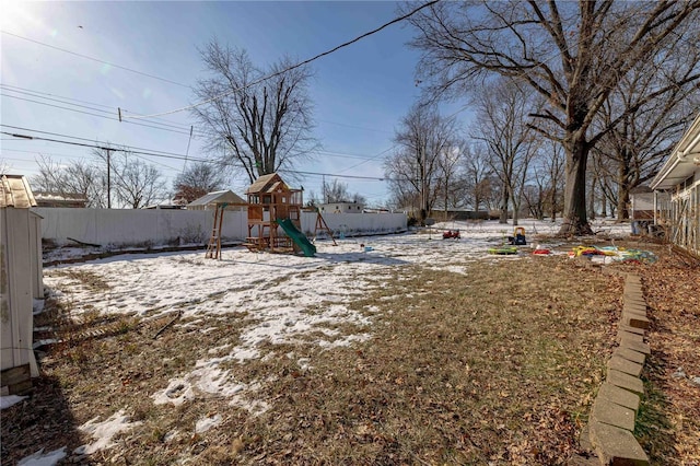 snowy yard featuring a playground