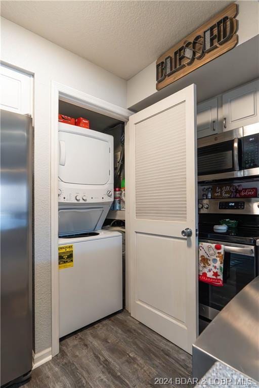 laundry room with a textured ceiling, stacked washer and dryer, and dark hardwood / wood-style floors