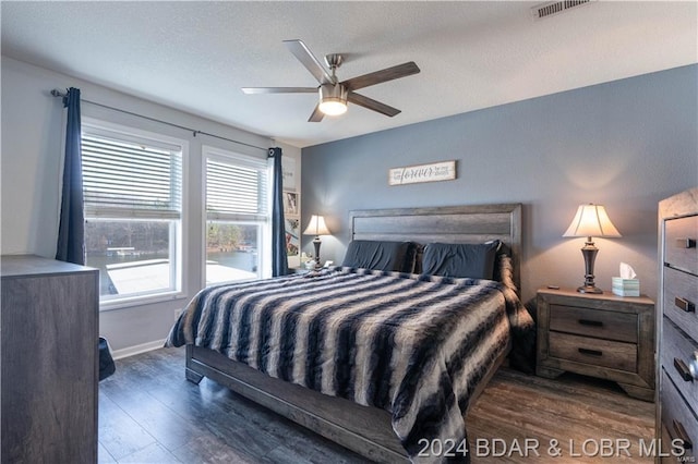 bedroom featuring a textured ceiling, ceiling fan, and dark wood-type flooring