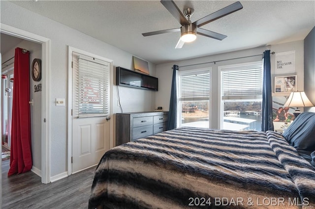 bedroom with a textured ceiling, ceiling fan, and dark wood-type flooring