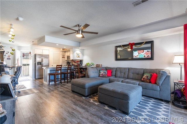 living room with ceiling fan, dark hardwood / wood-style flooring, and a textured ceiling