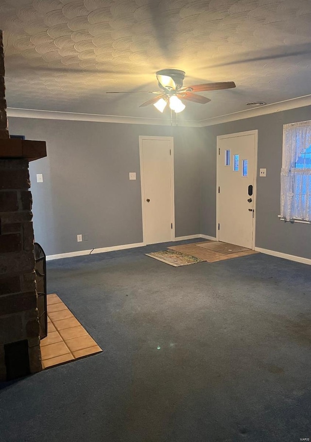 unfurnished living room with carpet flooring, ceiling fan, a fireplace, and crown molding