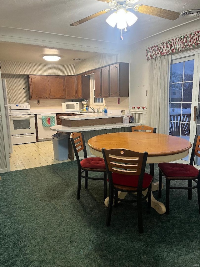 carpeted dining area featuring ceiling fan, ornamental molding, and sink