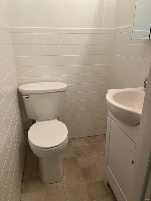 bathroom featuring vanity, toilet, and tile walls