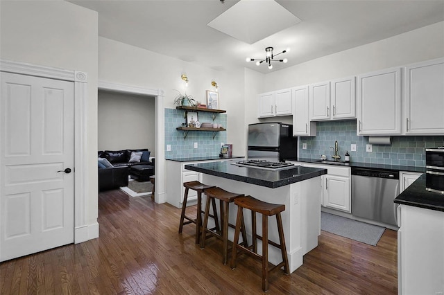 kitchen with white cabinetry, sink, stainless steel appliances, decorative backsplash, and a kitchen island