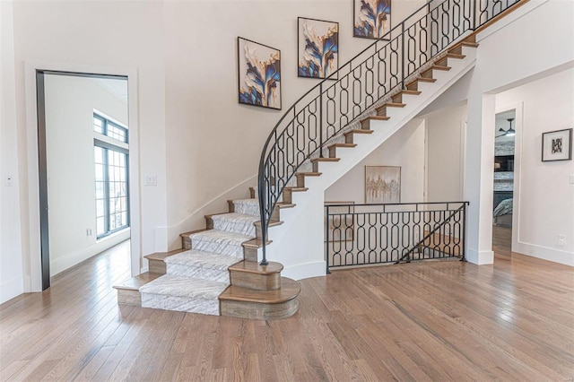 stairway featuring a high ceiling, hardwood / wood-style flooring, and ceiling fan