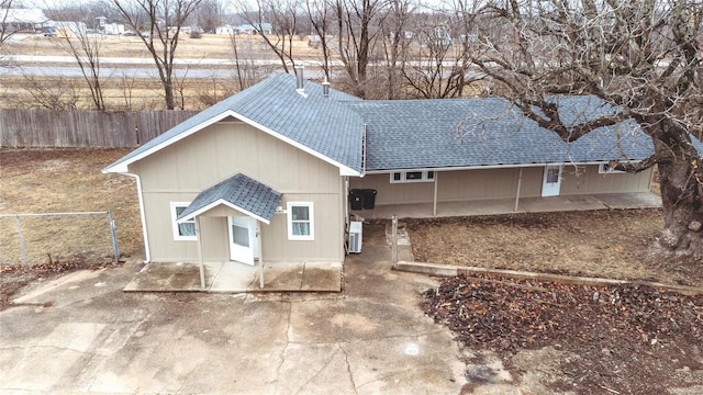 ranch-style house featuring a shingled roof, a patio area, and fence