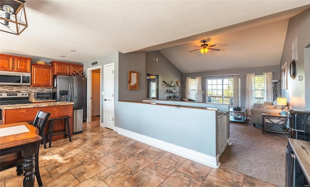 kitchen with lofted ceiling, backsplash, a breakfast bar area, ceiling fan, and stainless steel appliances