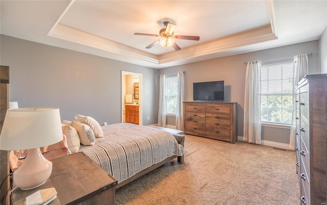 carpeted bedroom featuring a tray ceiling, connected bathroom, and ceiling fan