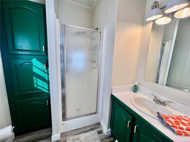 bathroom featuring hardwood / wood-style flooring, vanity, a shower with shower door, and crown molding