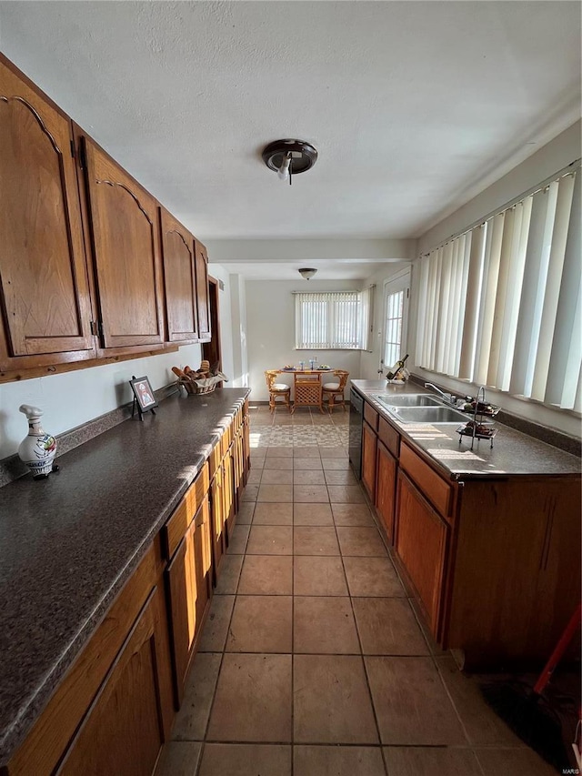 kitchen with dishwasher, sink, a textured ceiling, and tile patterned flooring