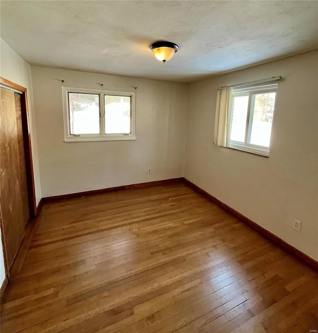 spare room with a textured ceiling and light wood-type flooring