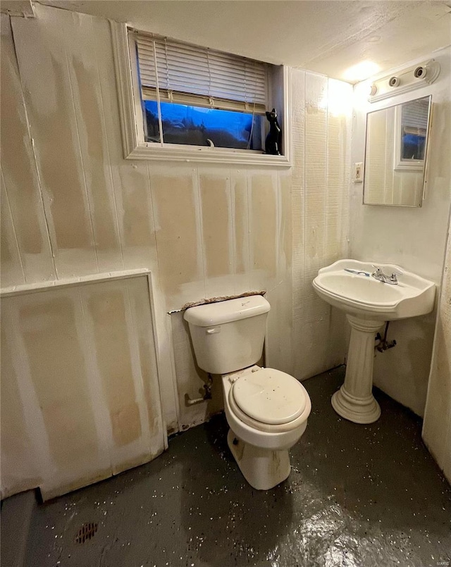 bathroom featuring toilet, concrete flooring, and sink