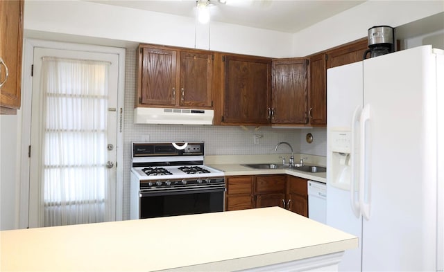 kitchen with kitchen peninsula, white appliances, backsplash, and sink