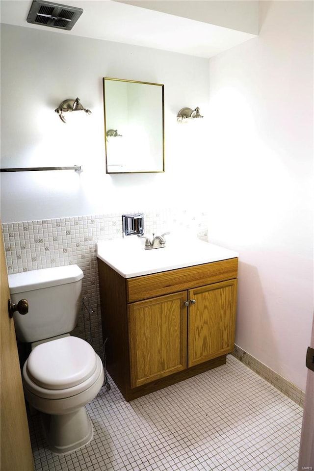 bathroom featuring tile patterned floors, vanity, toilet, and tile walls