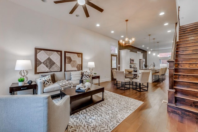 living room featuring ceiling fan with notable chandelier and dark wood-type flooring