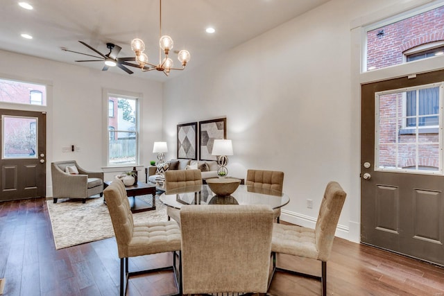 dining area with ceiling fan with notable chandelier and dark hardwood / wood-style floors