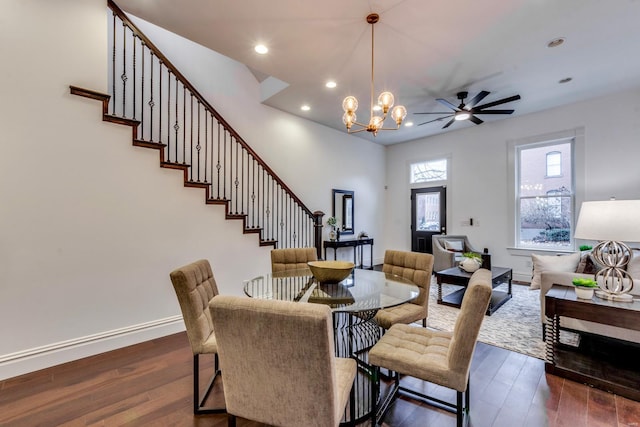 dining space featuring dark wood-type flooring and ceiling fan with notable chandelier