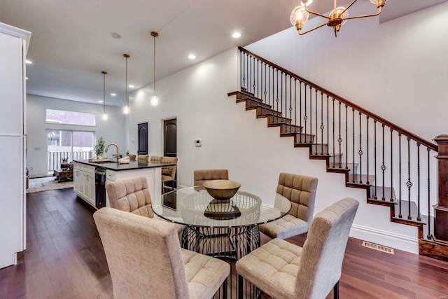 dining area featuring a towering ceiling, an inviting chandelier, dark wood-type flooring, and sink