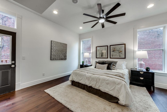 bedroom with ceiling fan, dark hardwood / wood-style flooring, and multiple windows