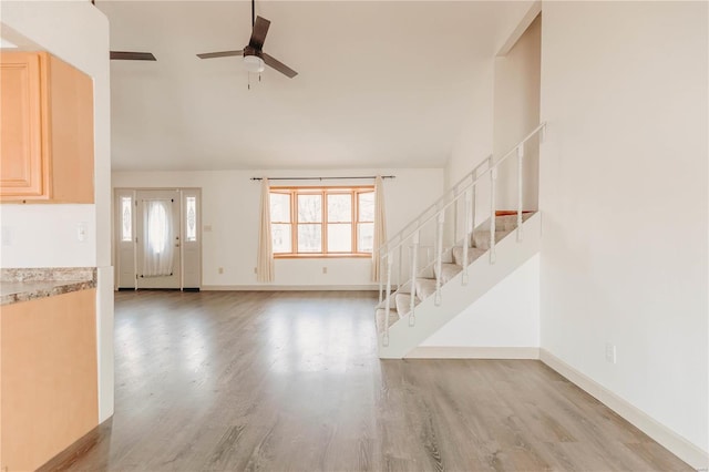 unfurnished living room featuring vaulted ceiling, ceiling fan, and light hardwood / wood-style floors