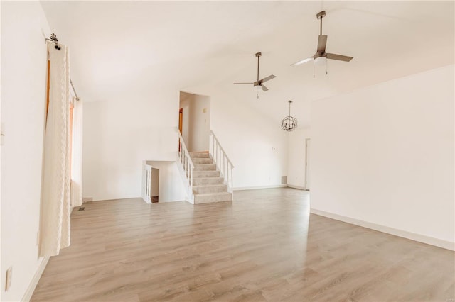 unfurnished living room with ceiling fan with notable chandelier and light wood-type flooring