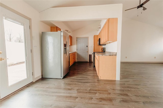 kitchen featuring vaulted ceiling, plenty of natural light, fridge with ice dispenser, and light wood-type flooring