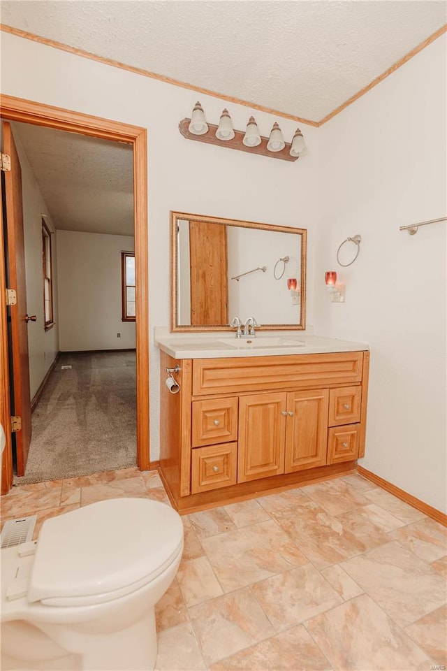 bathroom with vanity, ornamental molding, toilet, and a textured ceiling