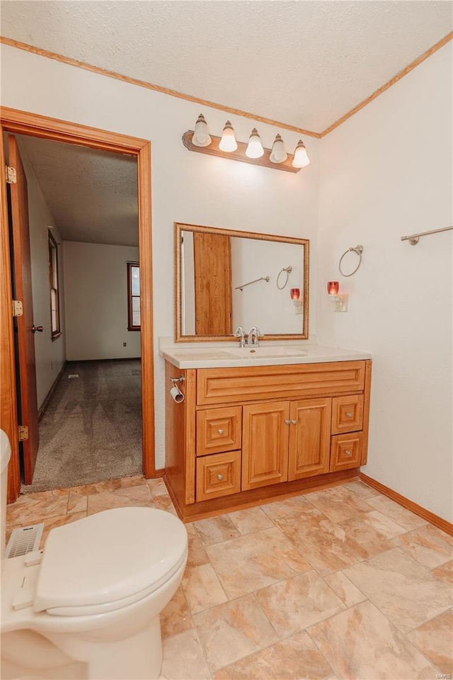 bathroom featuring ornamental molding, vanity, toilet, and a textured ceiling