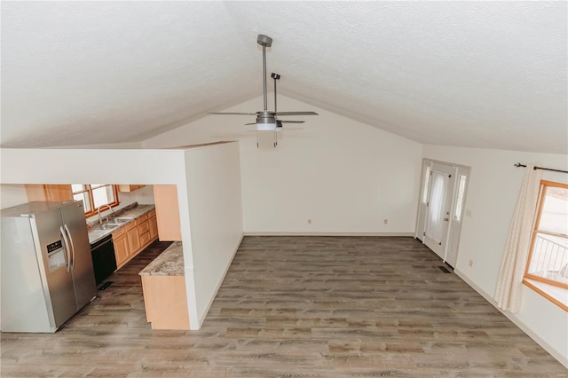 unfurnished living room featuring vaulted ceiling, sink, ceiling fan, dark wood-type flooring, and a textured ceiling