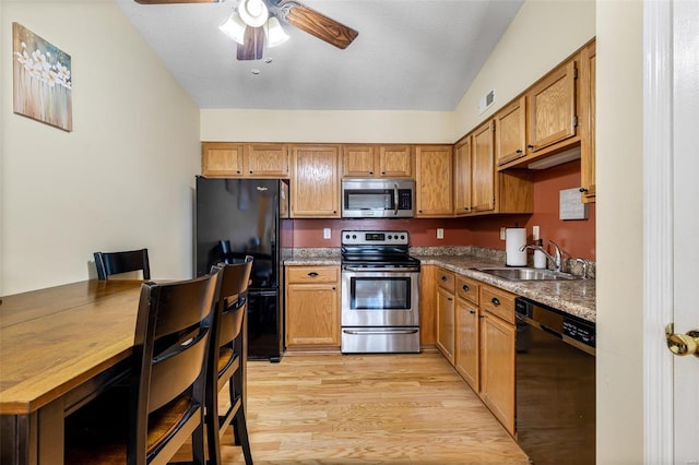 kitchen with black appliances, sink, ceiling fan, light stone counters, and light hardwood / wood-style flooring