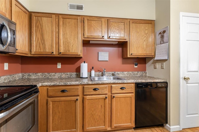 kitchen with appliances with stainless steel finishes, light hardwood / wood-style floors, and sink