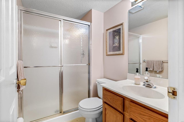 bathroom featuring a textured ceiling, toilet, a shower with door, and vanity