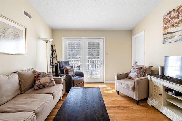 living room with a textured ceiling and light hardwood / wood-style flooring