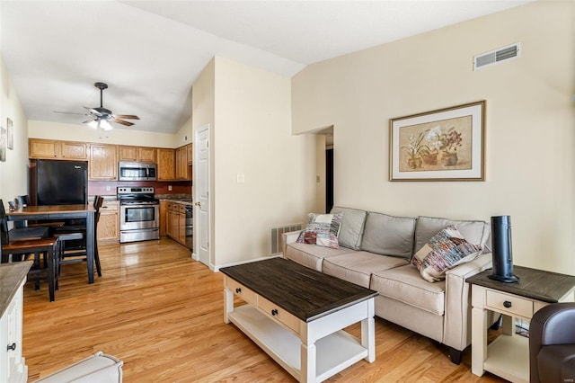 living room with light wood-type flooring, vaulted ceiling, and ceiling fan