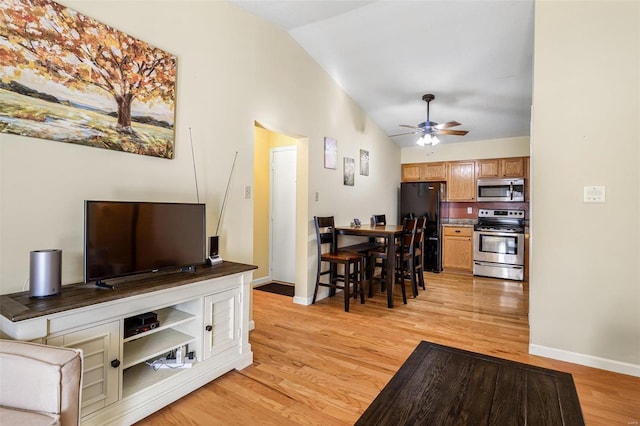 living room with ceiling fan, vaulted ceiling, and light hardwood / wood-style flooring