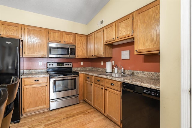 kitchen featuring sink, black appliances, lofted ceiling, and light hardwood / wood-style flooring