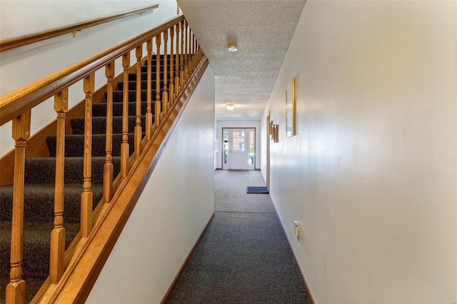 stairway with a textured ceiling and carpet flooring