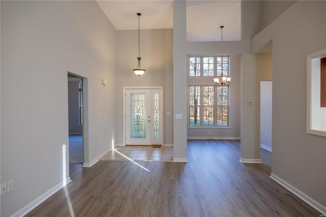 foyer featuring plenty of natural light, a towering ceiling, a chandelier, and wood-type flooring