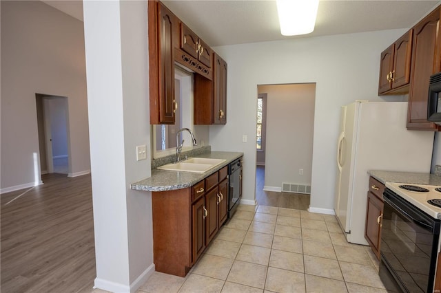 kitchen featuring light tile patterned floors, light stone counters, black appliances, and sink