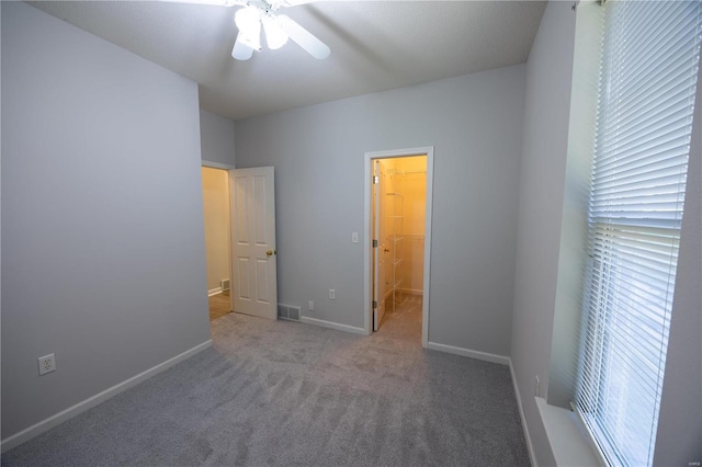 unfurnished bedroom with carpet, a spacious closet, a closet, and ceiling fan