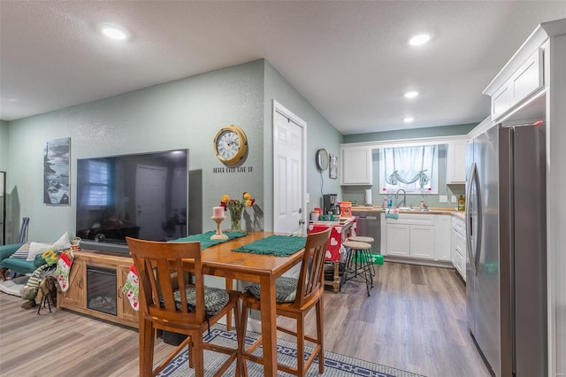 dining space with sink, light hardwood / wood-style floors, and a textured ceiling