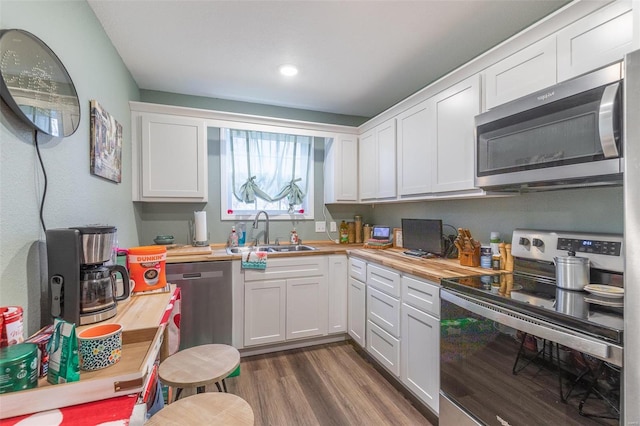 kitchen featuring white cabinets, butcher block countertops, sink, and appliances with stainless steel finishes