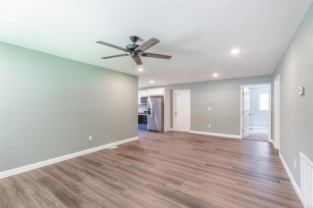 empty room featuring ceiling fan, wood-type flooring, and a textured ceiling