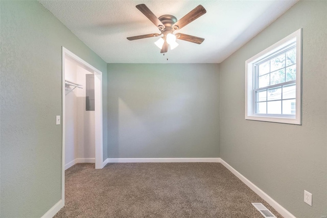 carpeted empty room with ceiling fan and a textured ceiling