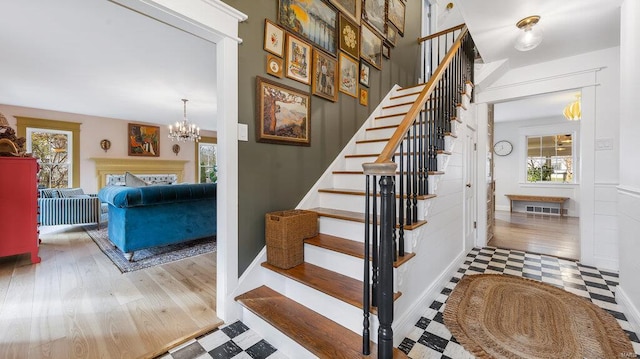 stairway with a wealth of natural light and a notable chandelier