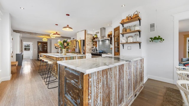 kitchen featuring kitchen peninsula, a kitchen bar, gas range oven, hanging light fixtures, and range hood