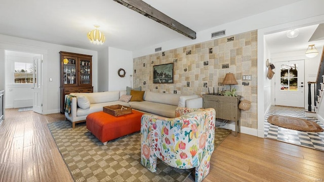 living room with beam ceiling, light wood-type flooring, and a chandelier