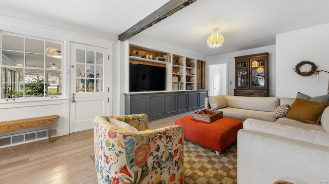 living room with beam ceiling, built in features, light hardwood / wood-style floors, and a notable chandelier