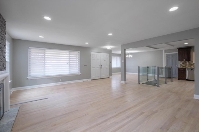 unfurnished living room featuring a chandelier and light hardwood / wood-style floors